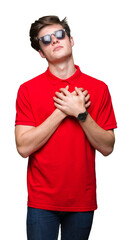 Wall Mural - Young handsome man wearing sunglasses over isolated background smiling with hands on chest with closed eyes and grateful gesture on face. Health concept.