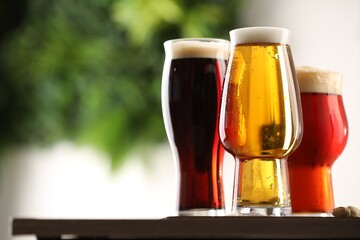 Wall Mural - Glasses with different types of beer on table against blurred background, closeup. Space for text