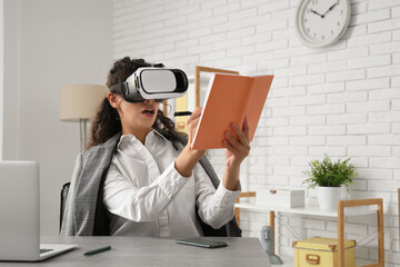 Wall Mural - Young African-American businesswoman in VR glasses working at table in office