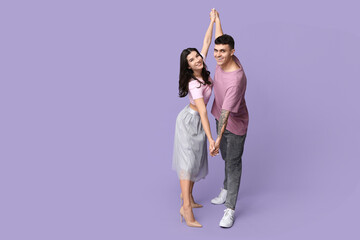 Poster - Beautiful young couple dancing on lilac background