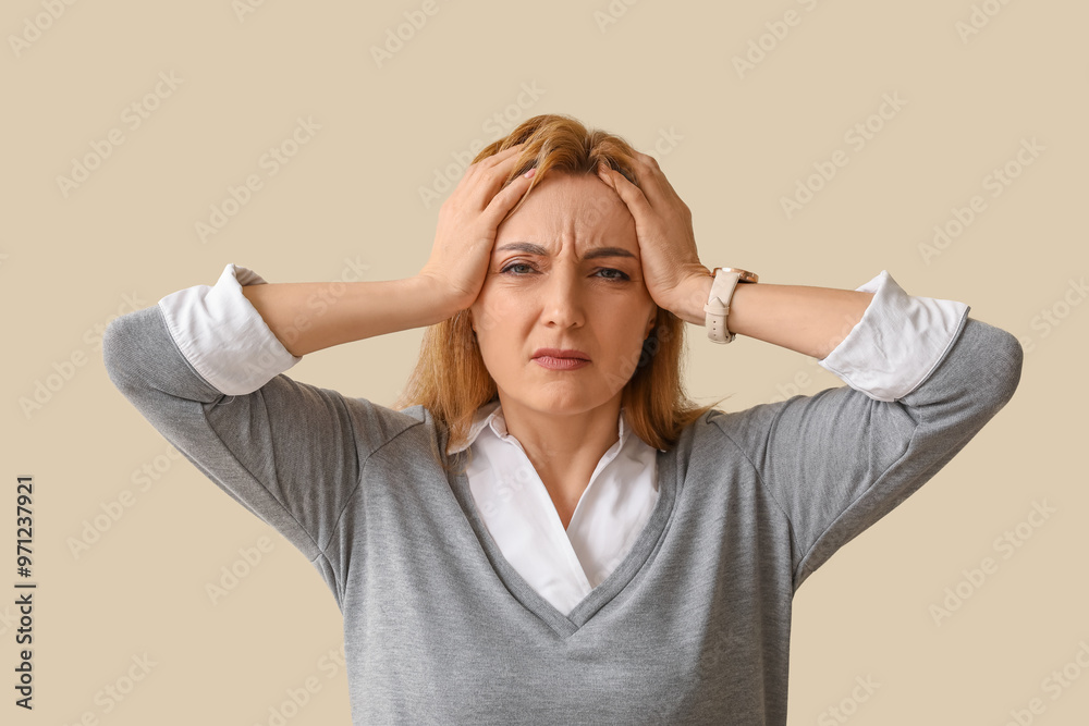 Upset adult woman suffering from headache on light background