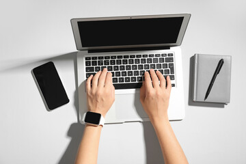 Wall Mural - Female hands with laptop, notebook and mobile phone on grey background