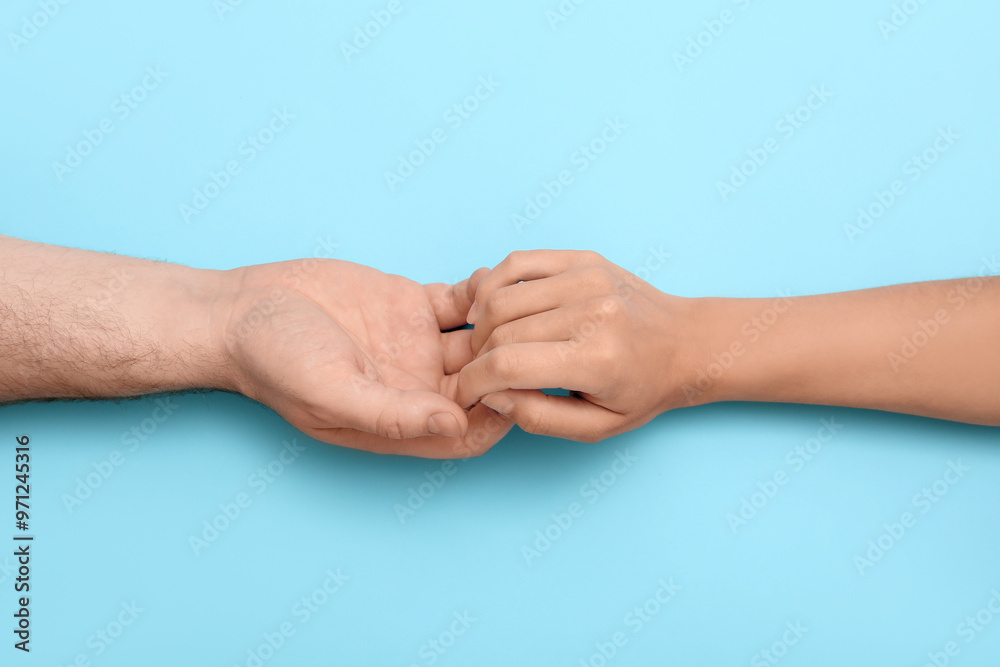 Loving young couple holding hands on blue background
