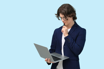 Male programmer in eyeglasses with laptop and pen on blue background
