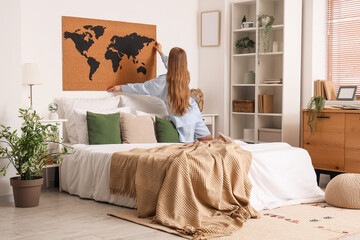 Canvas Print - Young woman hanging world map on white wall in cozy bedroom