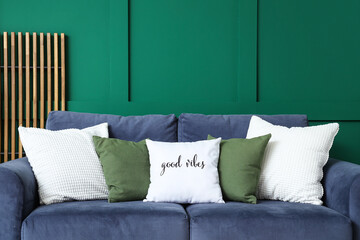 Poster - Comfortable sofa with different pillows near green wall in living room