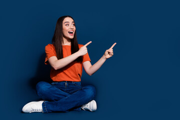 Poster - Photo of positive cheerful glad woman wear stylish clothes sit floor look empty space isolated on dark blue color background