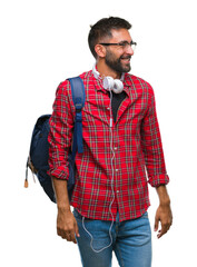 Wall Mural - Adult hispanic student man wearing headphones and backpack over isolated background looking away to side with smile on face, natural expression. Laughing confident.