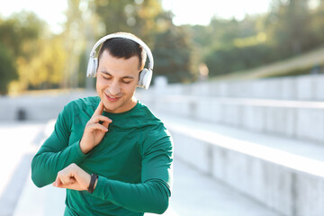 Canvas Print - Sporty young man checking pulse after training outdoors