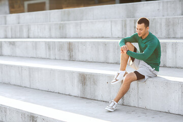 Canvas Print - Sporty young man looking at watch outdoors