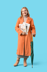 Poster - Beautiful mature happy woman with magazines and umbrella on blue background