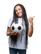 © Krakenimages.com - Young braided hair african american girl holding soccer ball over isolated background pointing and showing with thumb up to the side with happy face smiling