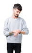 © Krakenimages.com - Young handsome man wearing sweatshirt over isolated background Checking the time on wrist watch, relaxed and confident