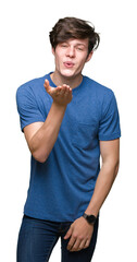 Wall Mural - Young handsome man wearing blue t-shirt over isolated background looking at the camera blowing a kiss with hand on air being lovely and sexy. Love expression.