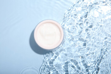 Poster - Cosmetic product. Jar with cream in water on light blue background, top view