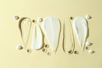 Sticker - Smears of different cosmetic products on beige background, flat lay