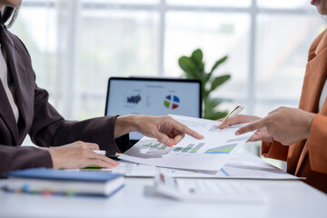 Businesswomen reviewing and analyzing financial charts at an office desk