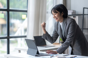 Wall Mural - Excited businesswoman celebrating success looking at laptop in modern office