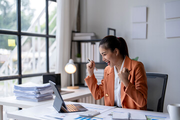 Wall Mural - Young asian businesswoman celebrating success working in modern office