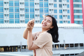 beautiful asian young woman holding sparklers firework and laughing in new year eve celebration standing in roof top outdoor with urban building background