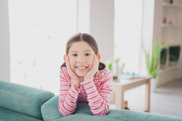 Sticker - Close up photo of young happy funny kid little brunette girl staying at home spending holidays lying on couch isolated in her room