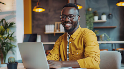 Poster - portrait of a male tech support worker sitting in modern office working on laptop