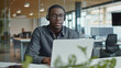 © Ali - portrait of a male tech support worker sitting in modern office working on laptop