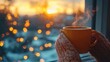 © KADER - Close-up of a woman's hand holding a steaming coffee mug by a window overlooking a winter garden at sunset, with space for text