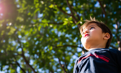 little boy 8-9 years old in blue t-shirt in park looking at sun