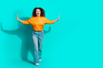 Poster - Full size photo of impressed positive woman dressed orange shirt palms pushing objects empty space isolated on teal color background