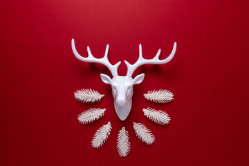 Wall Mural - White reindeer with white pine tree branches on red backdrop. Minimal New Year or Christmas background concept.