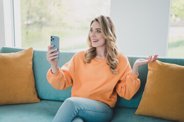 Photo portrait of attractive young woman sit couch talk video call dressed orange outfit cozy day light home interior living room