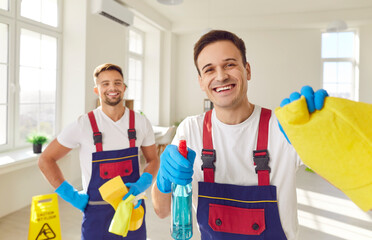 Male cleaners, professional cleaning service team working, happy guys in overalls employed to clean rooms, holding spray bottle for surface clean, performing office duties, washing