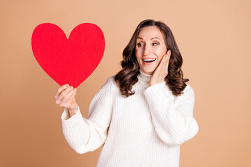 Poster - Photo of adorable lovely woman wear white trendy clothes hold heart shape isolated on beige color background