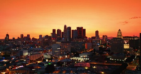 Wall Mural - Skies painted orange above the busy American metropolis. Twilight view of Los Angeles from rising drone.