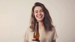 © Bonsales - Smiling young woman with long hair holding a beer bottle against a plain background. She looks happy and carefree, enjoying her time