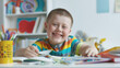 © Bonsales - Smiling boy with Down syndrome drawing at a desk in a colorful room. His joyful expression and creative activity create a cheerful and engaging atmosphere