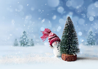 Wall Mural - One little snowmen in caps with Christmas tree on snow in the winter. Background with a funny snowman. Christmas card.