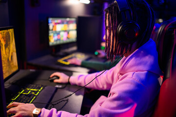 Side view of focused gamer sitting in cybercafe, playing video game.