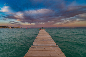 Beautiful sunset on a sandy beach in Mallorca, Spain, with vibrant clouds and a serene coastline, capturing the peaceful evening atmosphere.
