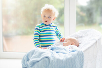 Wall Mural - child watching newborn baby in bassinet.