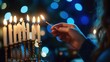 © Dassen - A hand lighting multiple candles on the Hanukkah menorah during the Jewish holiday celebration of Hanukka with bokeh lights.