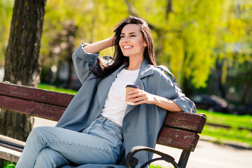 Poster - Photo portrait of brunette hair young dreamy woman drink cacao in trench and stylish jeans spend autumn outdoors breathing fresh air