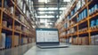 © Elmira - A laptop sits on a desk in a well-ordered warehouse, displaying inventory management software that assists in tracking stock and managing supplies effectively