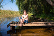 © Ruslan Russland - An 11 year old boy in swimming shorts sits on a wooden dock or bridge after swimming in a river.