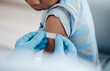 © peopleimages.com - Healthcare, child or plaster on arm with doctor hands, healing or injection site for vaccine. Kid, expert or bandage in clinic with PPE, support or wellness with flu shot for prevention or protection