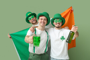 Wall Mural - Happy young men in leprechaun's hats with beer and flag of Ireland on green background. St. Patrick's Day celebration