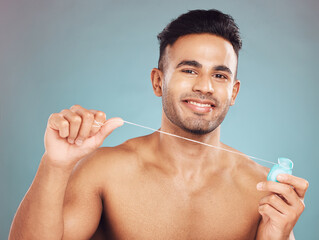 Poster - Studio, portrait and man with dental floss for wellness, gum hygiene and health with cleaning for fresh breath. Male model, teeth and string by blue background for mouth, gingivitis and oral care