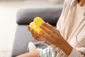 Wall Mural - Young woman with pill organizer at home, closeup