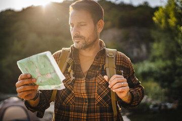 Adult man hiker stand and read map look for the right way